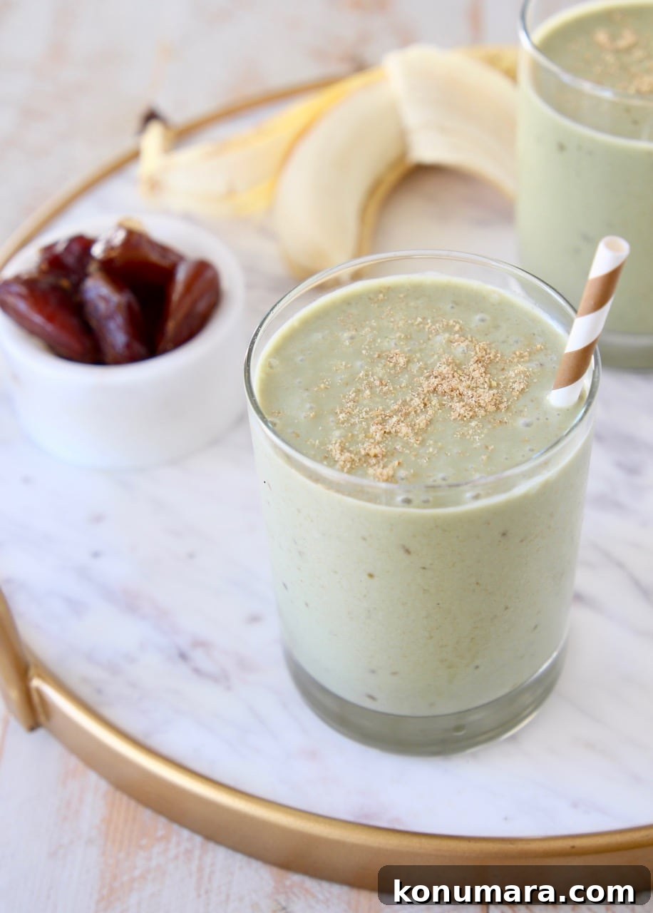 Creamy Banana and Date Protein Shake Recipe 4 Banana protein shake in glass with gold and white striped straw and ground flaxseed on top with peeled banana in background