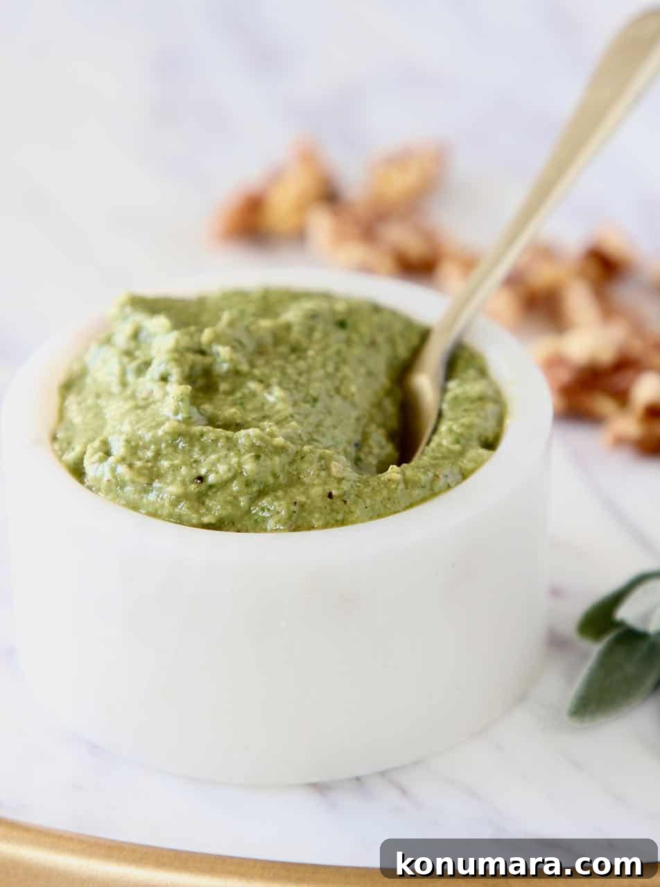 Fresh sage pesto in white bowl with gold spoon