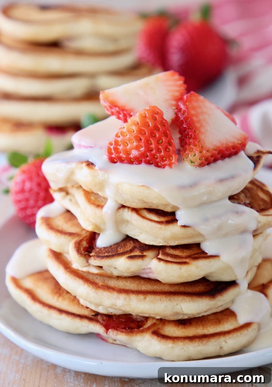 Strawberry pancakes topped with cream cheese syrup and fresh strawberries