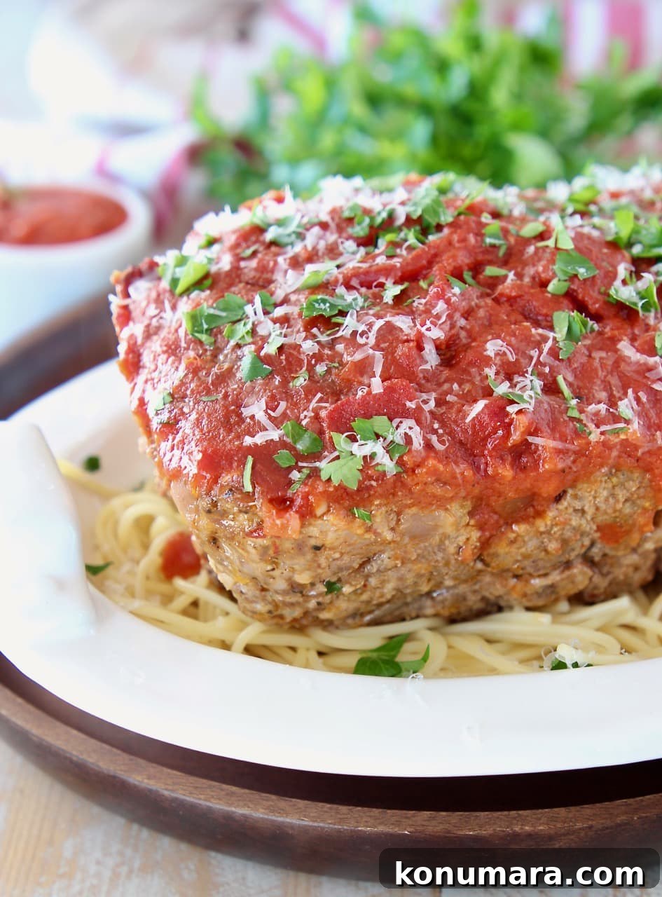 Classic Italian Meatloaf Recipe with Marinara Glaze 4 Italian meatloaf covered in marinara sauce on top of spaghetti in a white bowl