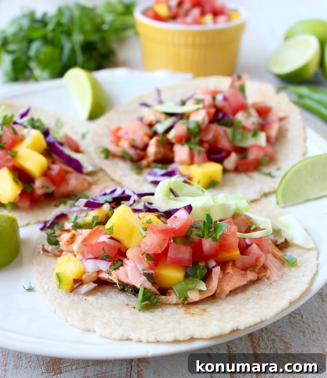 Fresh Mango Salsa Recipe with Lime, Cilantro and Red Onion 3 Corn tortillas topped with salmon and mango salsa on a white plate.