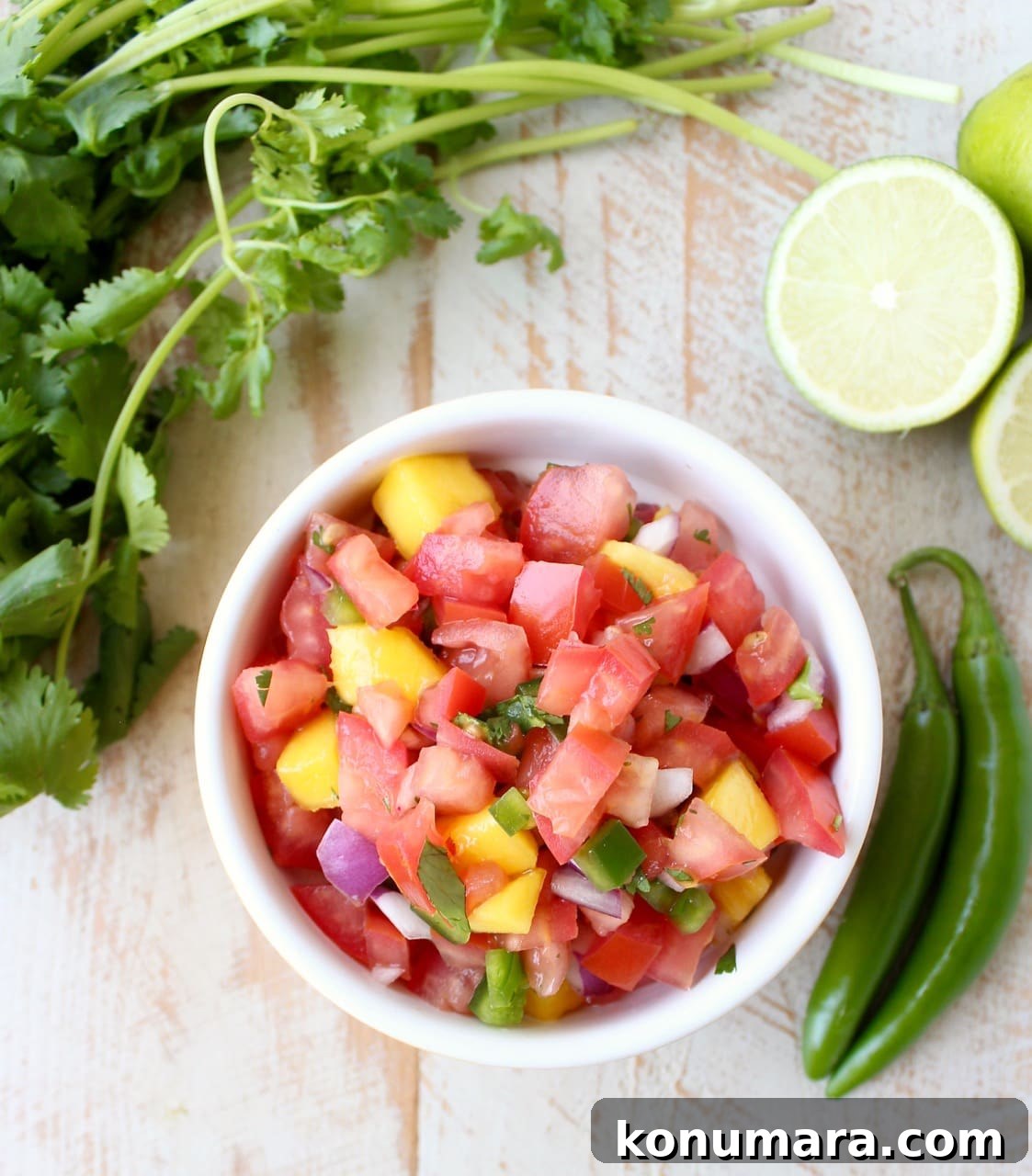 Fresh Mango Salsa Recipe with Lime, Cilantro and Red Onion 4 A yellow dish filled with diced tomatoes, jalapeños, mango, and onion.