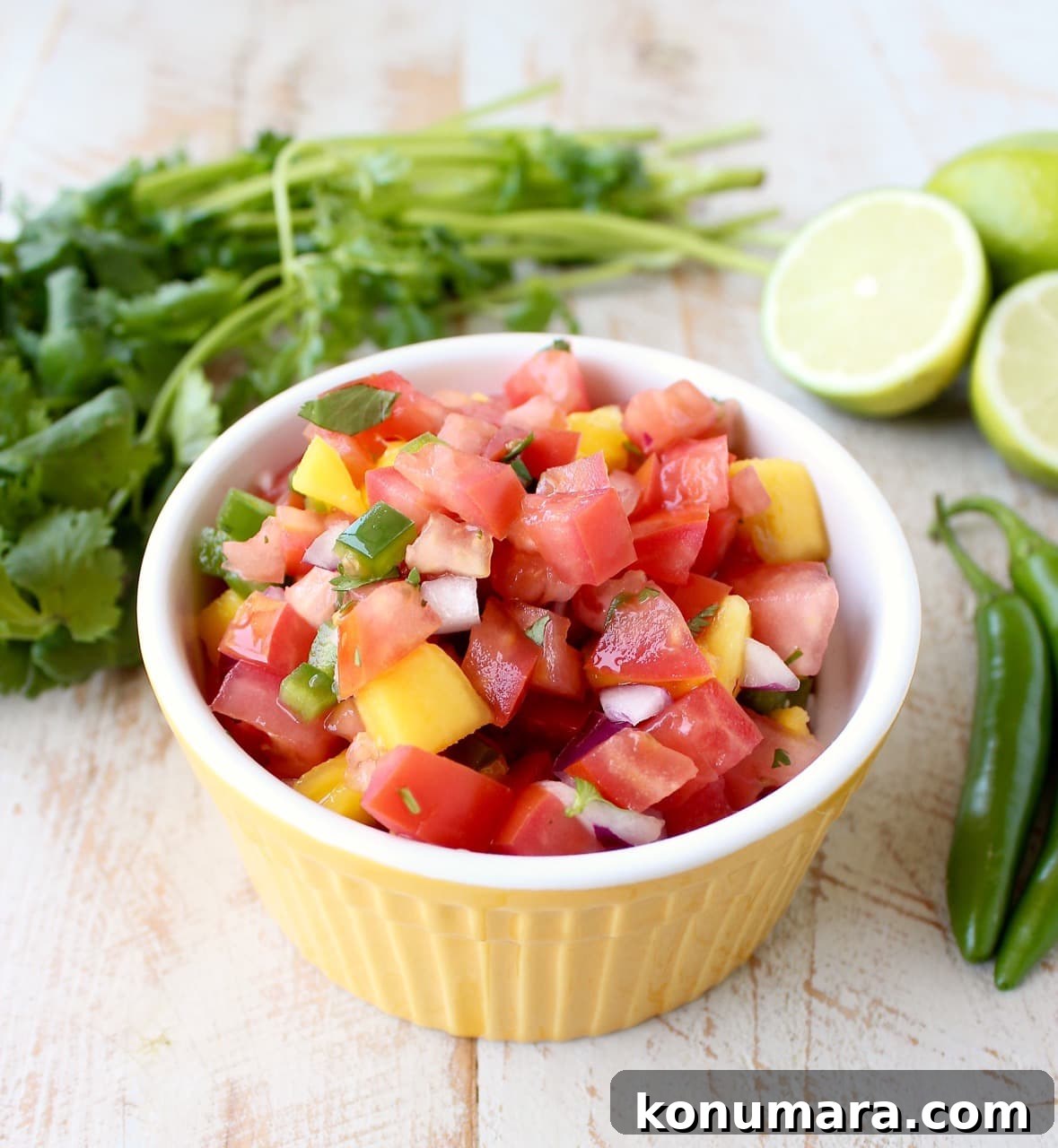 Fresh Mango Salsa Recipe with Lime, Cilantro and Red Onion 5 A yellow dish filled with diced tomatoes, jalapeños, mango, and onion.