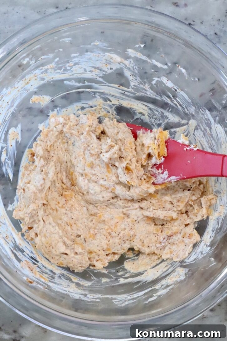Cheesy Cornbread Rolls Recipe: Soft, Melty Centers 6 seasoned cream cheese mixture in a glass bowl with a red spatula