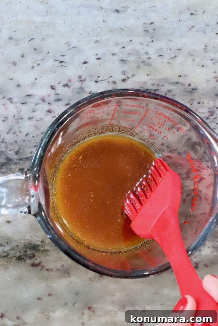 Cheesy Cornbread Rolls Recipe: Soft, Melty Centers 7 seasoned melted butter in a glass measuring cup with a red pastry brush