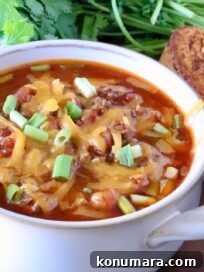 chili in a bowl topped with shredded cheddar cheese and diced green onions