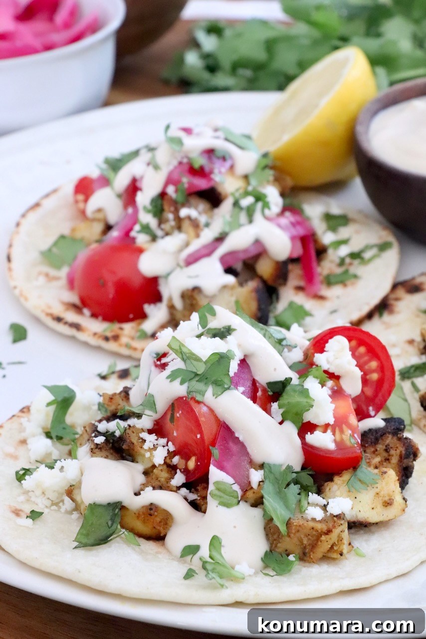 Chicken Shawarma Tacos with Garlic Yogurt Sauce 10 chicken shawarma tacos topped with garlic sauce on a plate