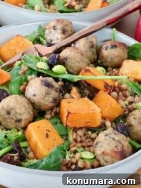 salad in a bowl topped with cranberry meatballs, butternut squash and edamame