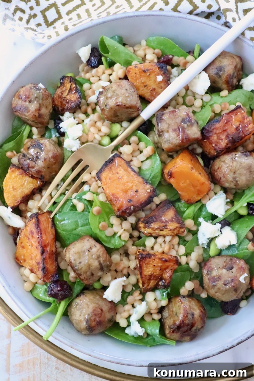 Autumn Harvest Grain Bowl with Roasted Squash and Quinoa 10 salad in a bowl with a fork, topped with chicken meatballs, butternut squash and couscous